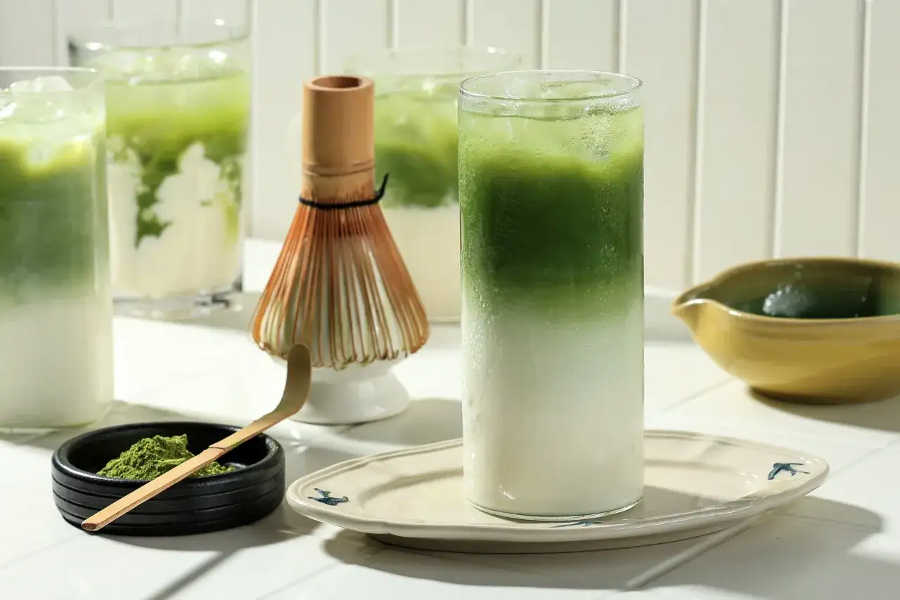 Orzeźwiające napoje z matchy, proszek matcha i bambusowa miotełka. Czy matcha odchudza? To pytanie nurtuje wiele os&oacute;b.