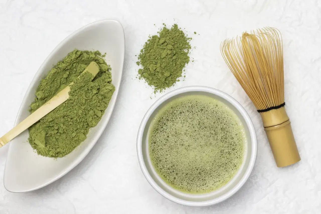 Zielony proszek matcha w miseczce, spieniony napój i bambusowa miotełka. Czy matcha jest zdrowa? Tak, to bogactwo antyoksydantów!