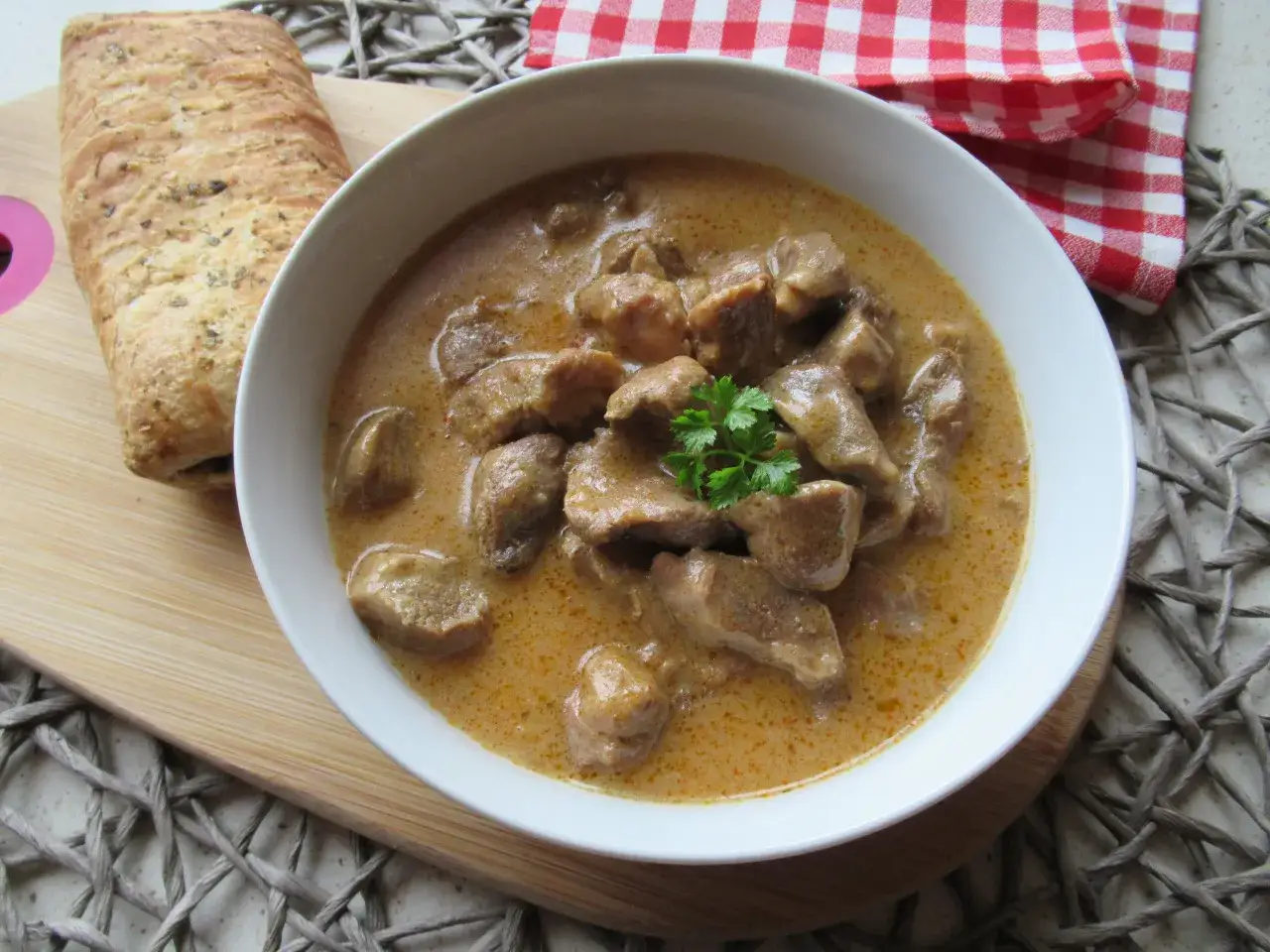 Aromaticzny, tradycyjny gulasz wieprzowy w kremowym sosie, udekorowany natką pietruszki, podany z pieczywem.