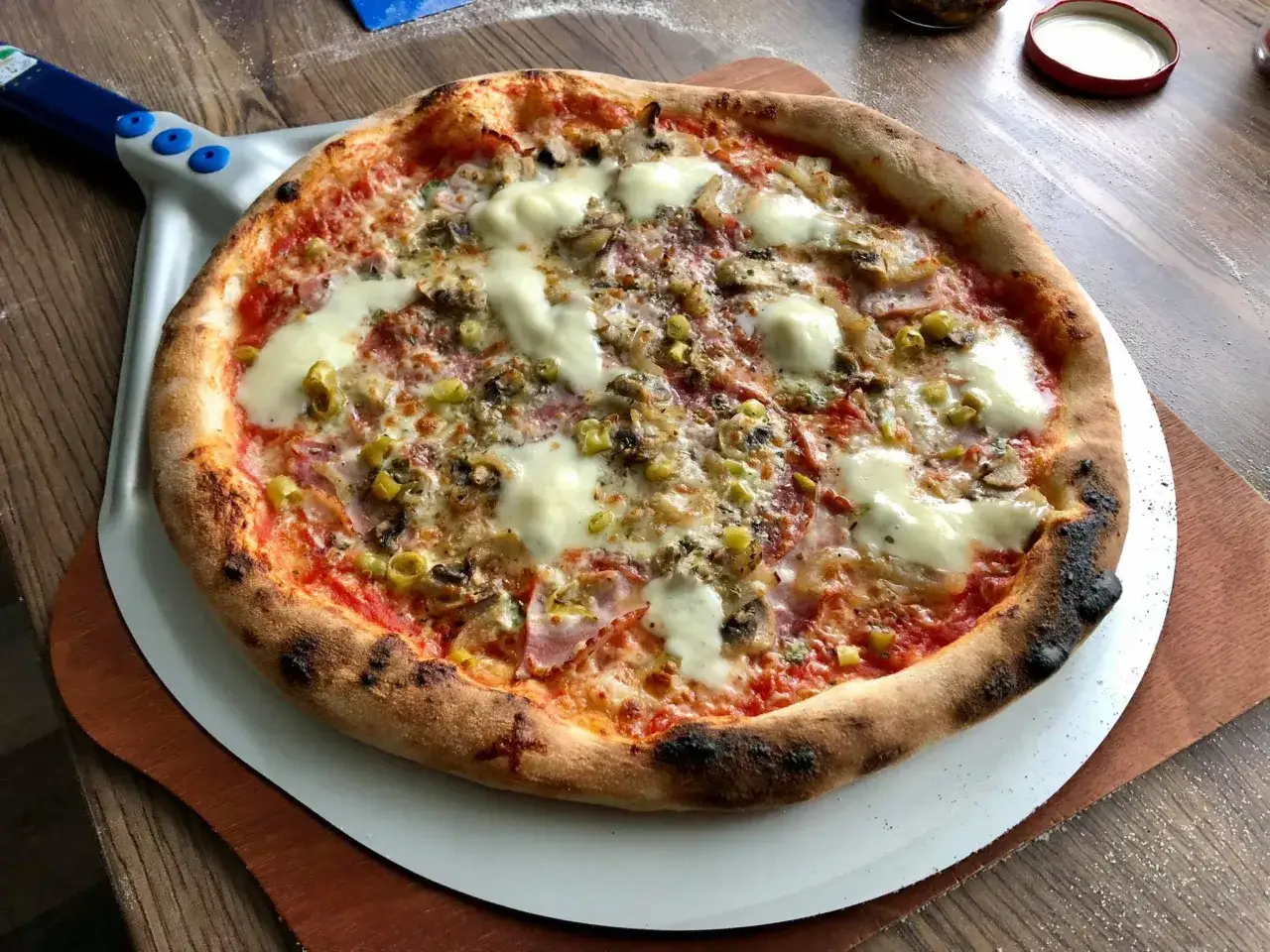 Pyszna pizza na łopacie, idealnie wypieczona. W jakiej temperaturze piec pizze, by uzyskać taki efekt? Wysoka!