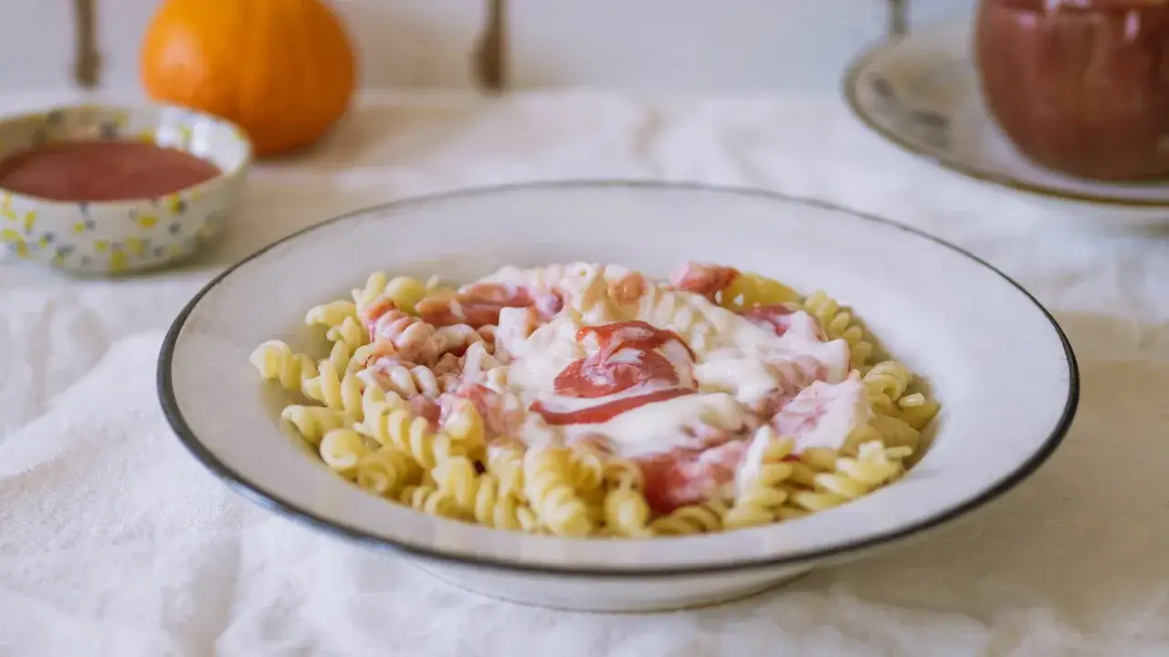 Fusilli z kremowym sosem i kawałkami owoców. Pyszny makaron na słodko, idealny na deser lub śniadanie.