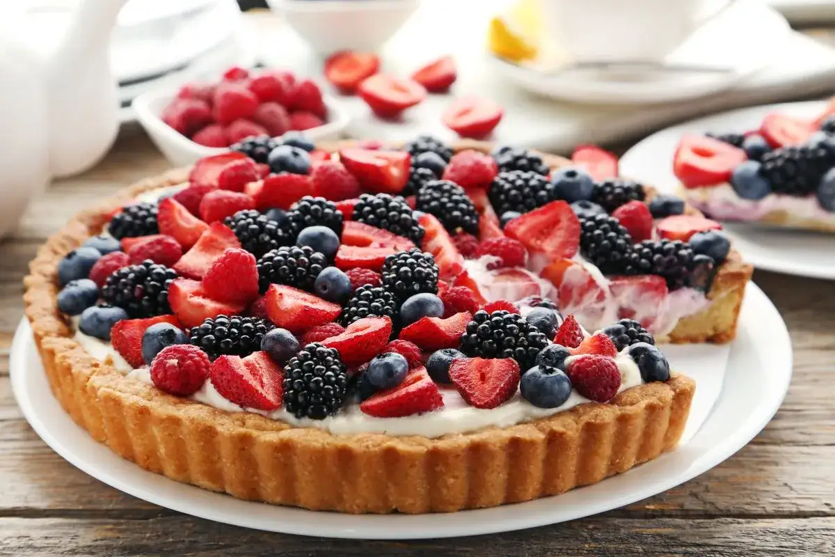 Pyszna tarta z mascarpone i owocami: malinami, borówkami, jeżynami i truskawkami, kusząca bogactwem smaków i kolorów.
