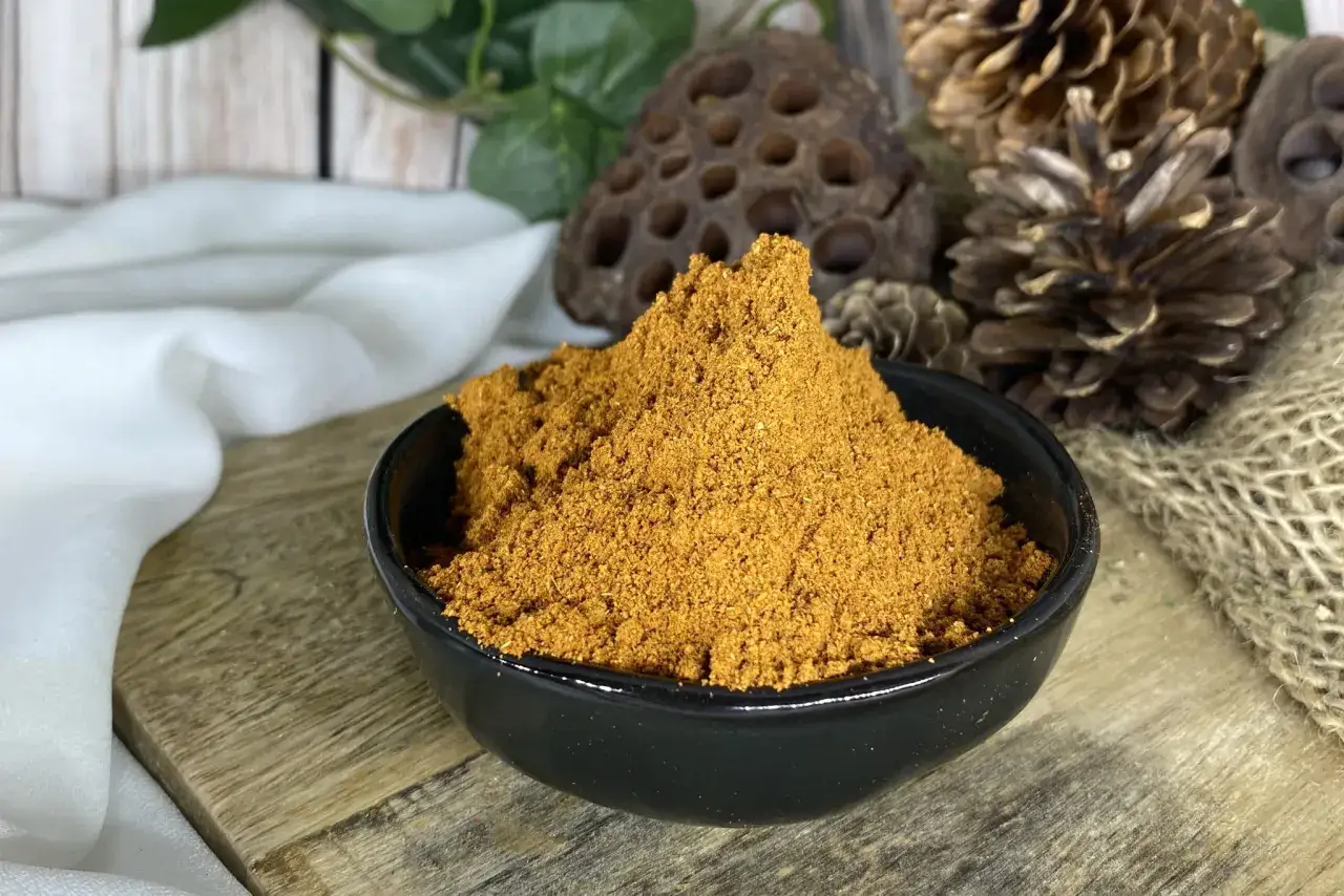 Aksamitny garam masala przepis w czarnej miseczce, otoczony szyszkami i białym jedwabiem.