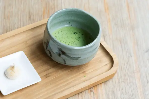 Zielone matcha w ceramicznej miseczce, obok małe bezy. Jak stosować keto matcha blue?