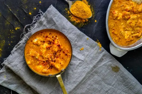 Aksamitny sos do butter masala, posypany papryką, obok łyżeczka kurkumy.