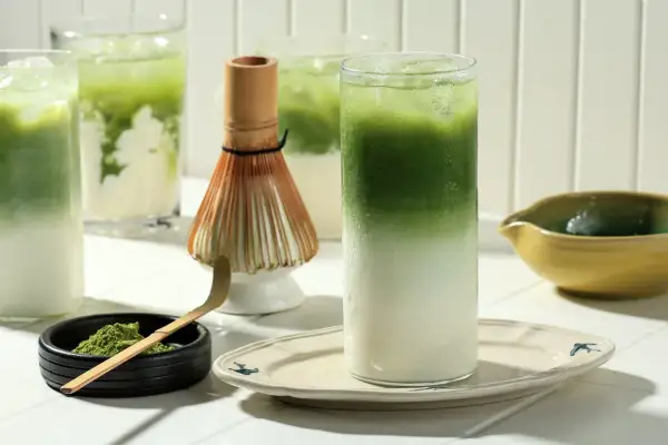 Zielony napój z lodem i mlekiem, proszek matcha, bambusowa miotełka. Czy matcha jest zdrowa? Tak, to napój pełen antyoksydantów.