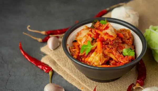 Miseczka z kimchi, obok suszone papryczki chili i czosnek.